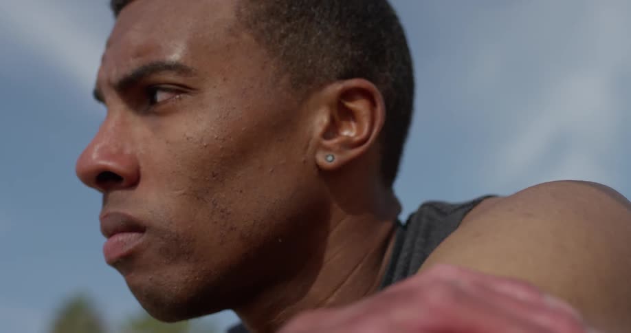 A man in a tank top looks concerned while standing outside