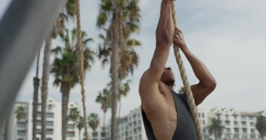 A young man climbs up a rope