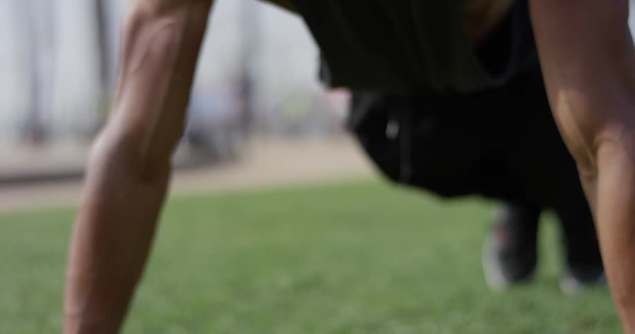 Man does push ups on a grassy field