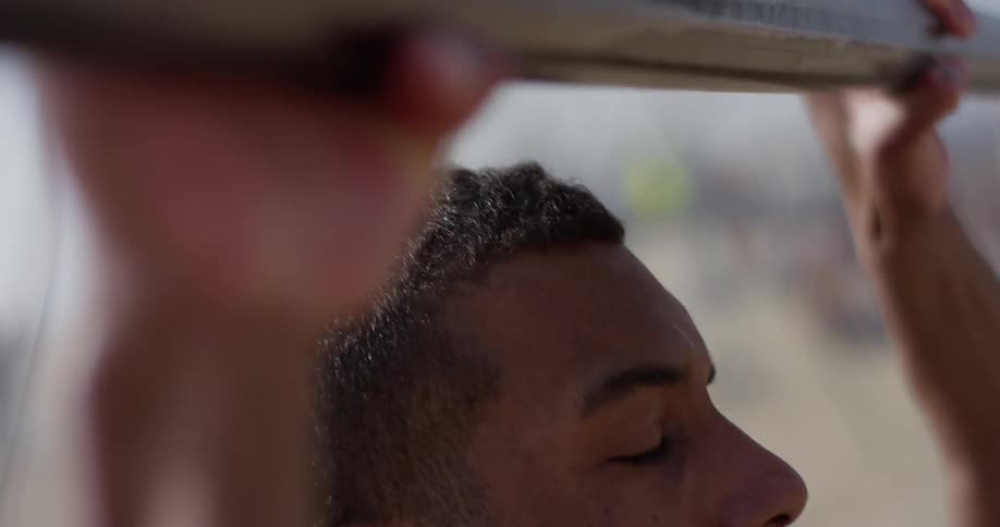 Black man holds pull up bar and pulls up on a sunny day