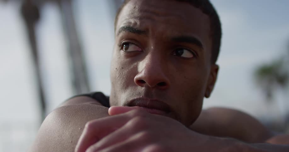 A man rests his chin on his arms on a beach