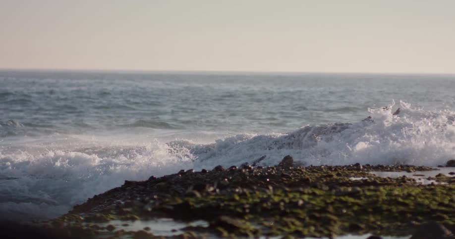 Ocean waves splash up and over a rocky shore