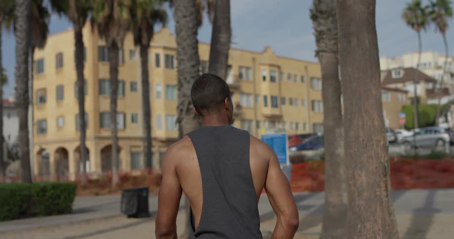 A black man walks across a beach while taking his surroundings