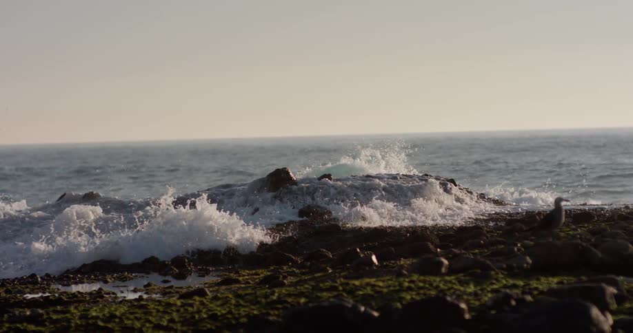 Ocean waves splash up and over the rocky shore
