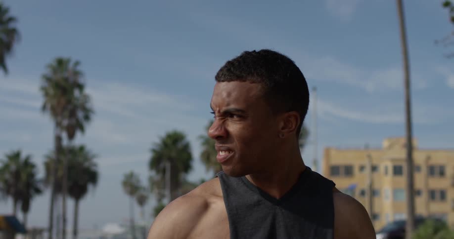 A black man walking through a city on a sunny day