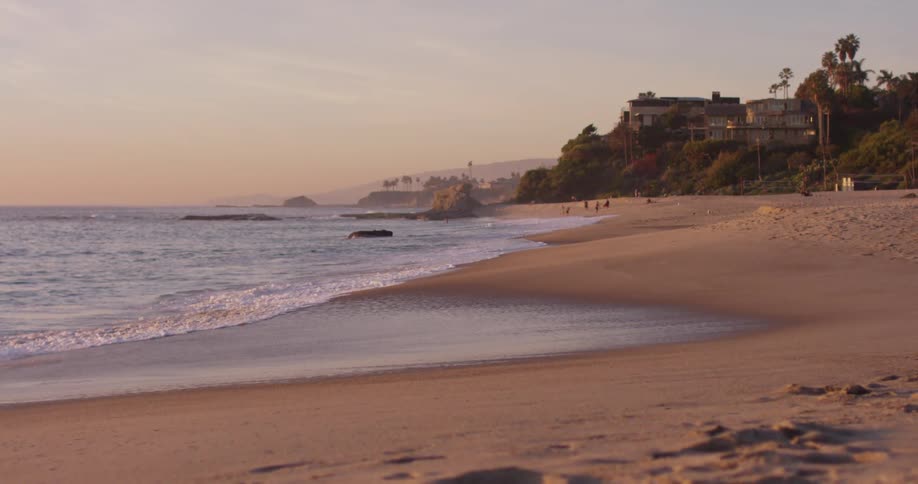 Ocean waves come to shore on a sandy tropical beach at sunset