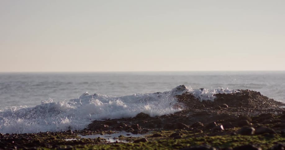 Waves crash onto rocks along the deserted shore