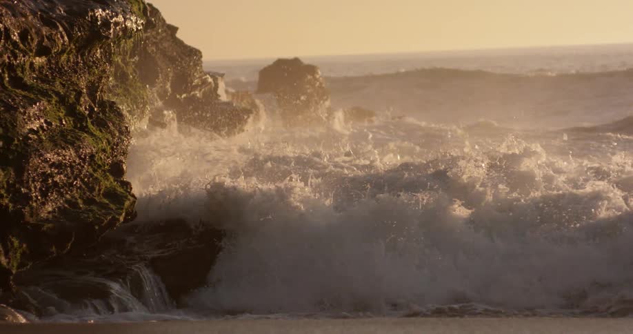 Waves crashing on rocks at sunset