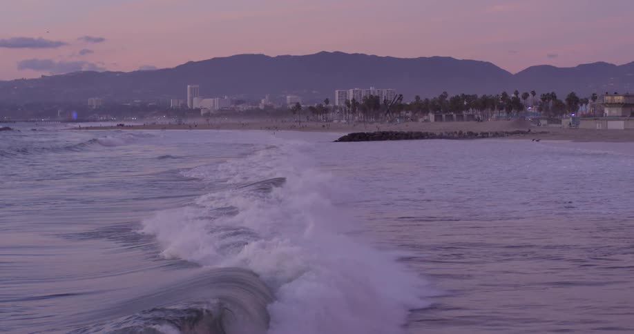 A wave rolling into a beach in the evening