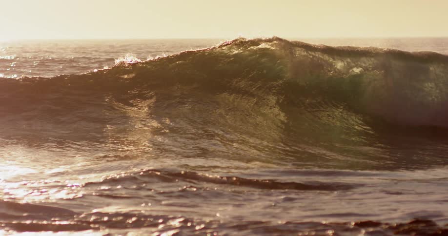 A surfer rides up and over a large wave