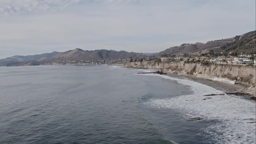 Ocean waves flow towards a shoreline with houses and buildings