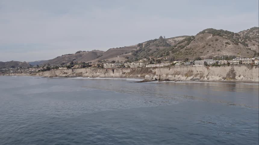 Buildings on shore near low mountains