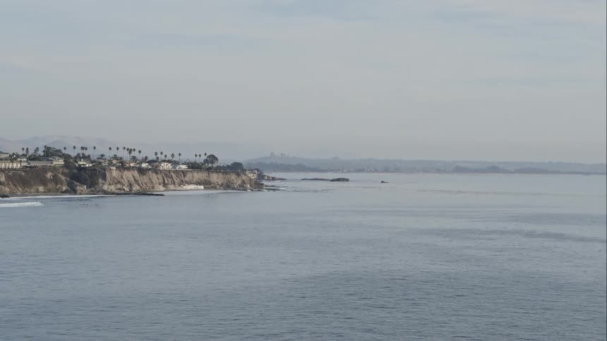 Palm trees and buildings on cliffs above the ocean on a cloudy day