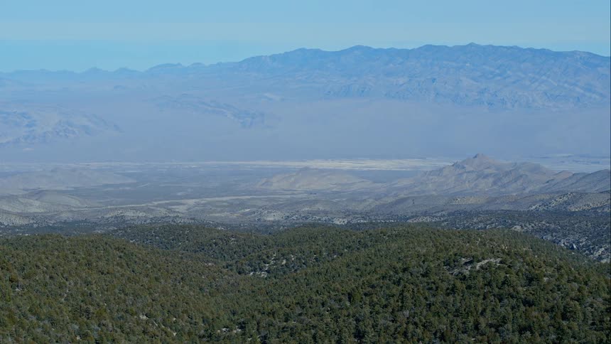 Mountains and trees sit under a blue sky