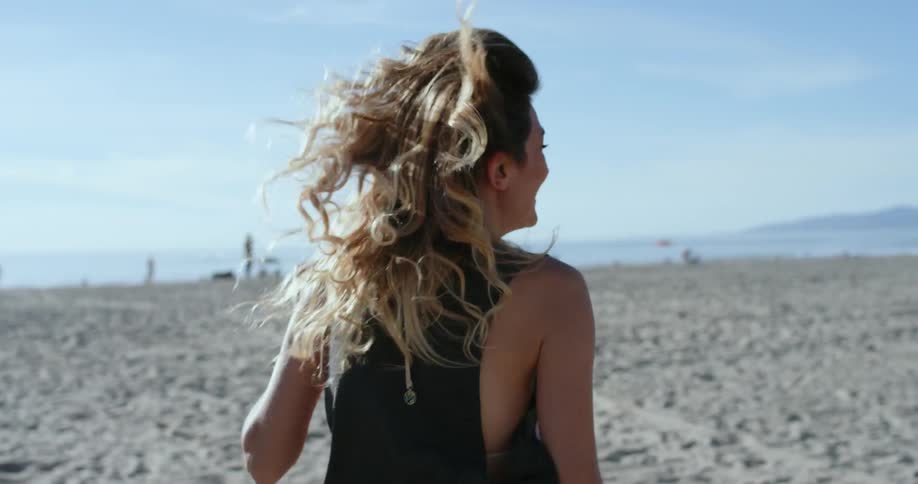 A young woman runs along the beach laughing