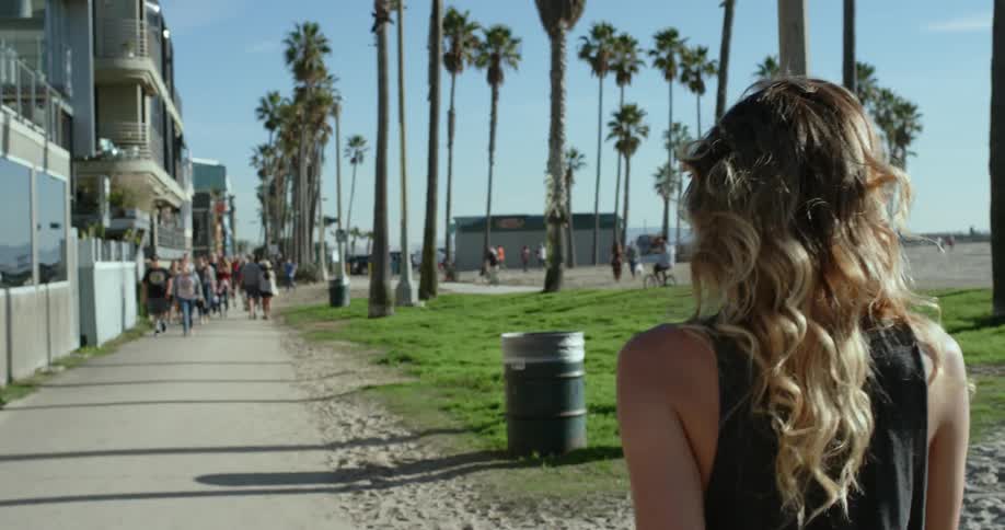 A woman walking on the pavement near a beach