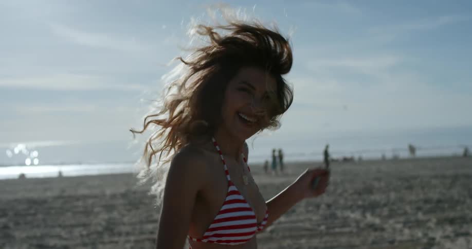 A woman on the beach running and laughing
