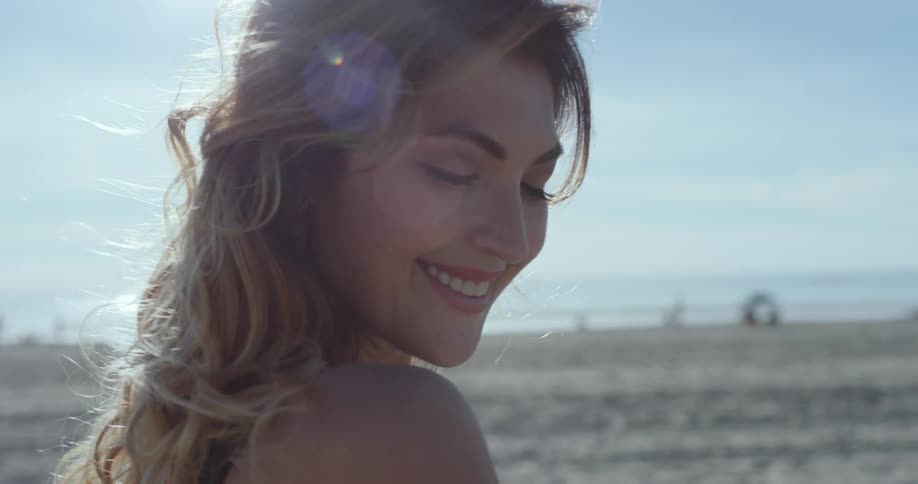 A young woman smiles and winks on a beach
