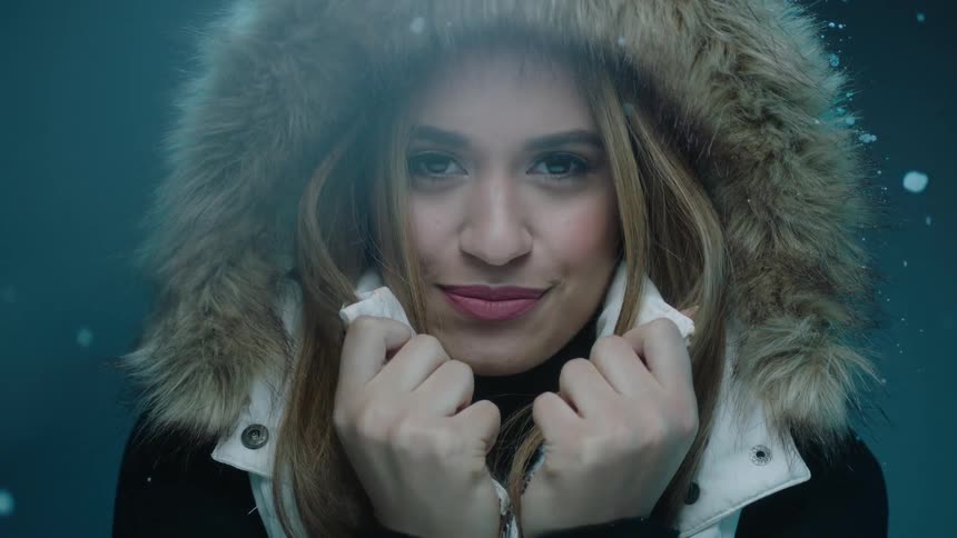 A blonde woman in a fur lined hood pulling her collar up
