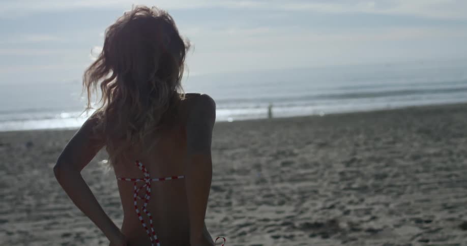 A woman runs across the beach toward the water
