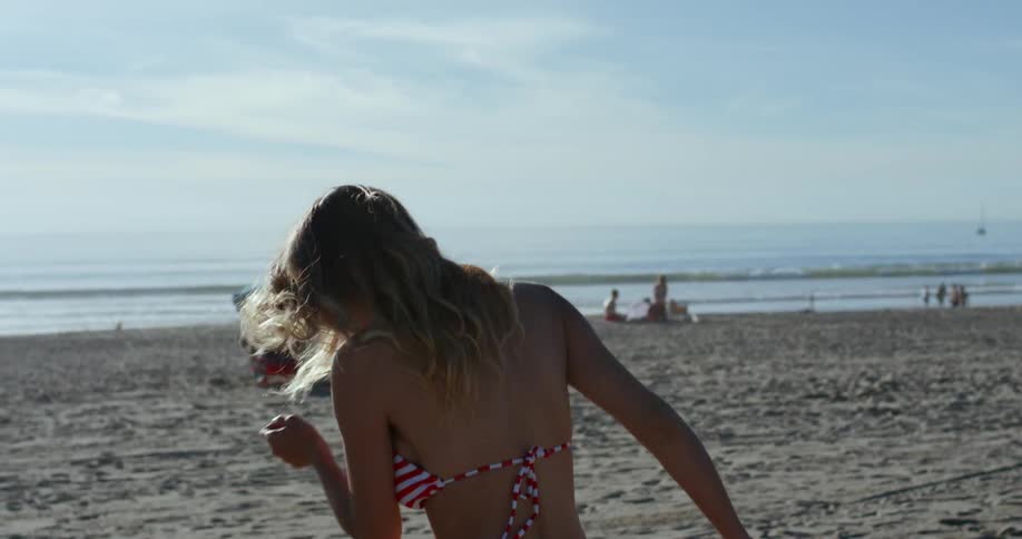 A woman on the beach running and smiling