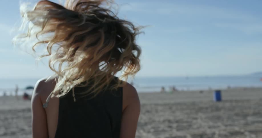 A white woman runs across a beach and laughs