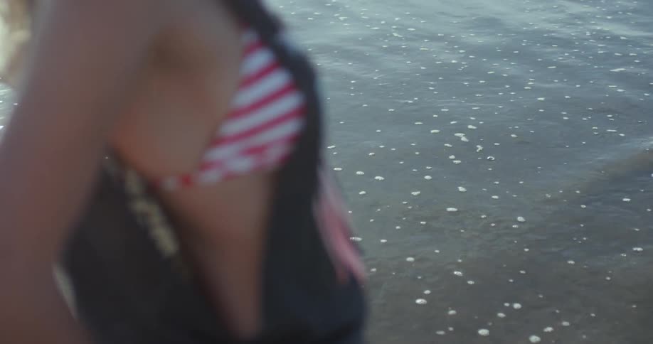 Woman in bikini and shirt standing by ocean