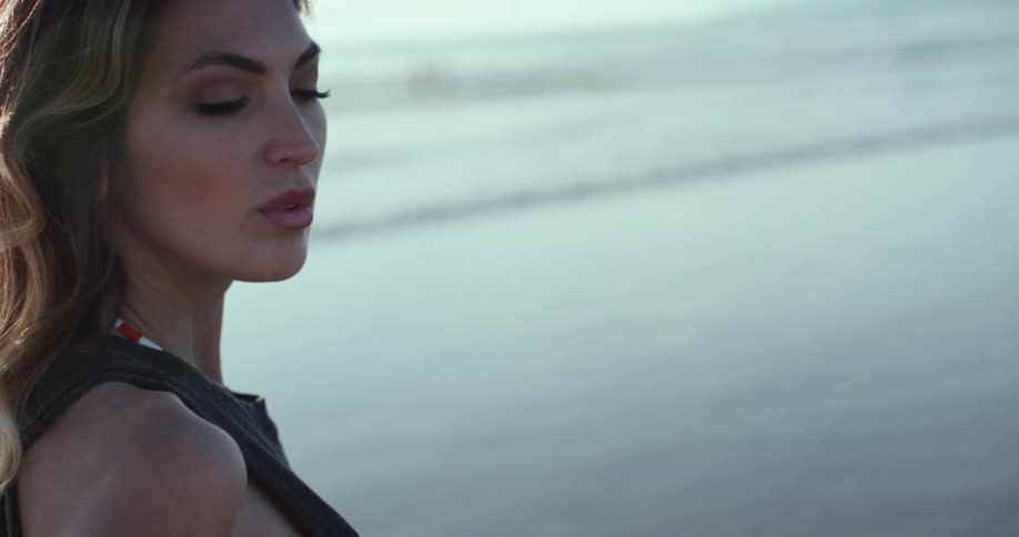 Woman in bikini stands on the shore of a calm beach