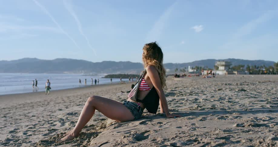 A woman sitting on the beach enjoying the sun