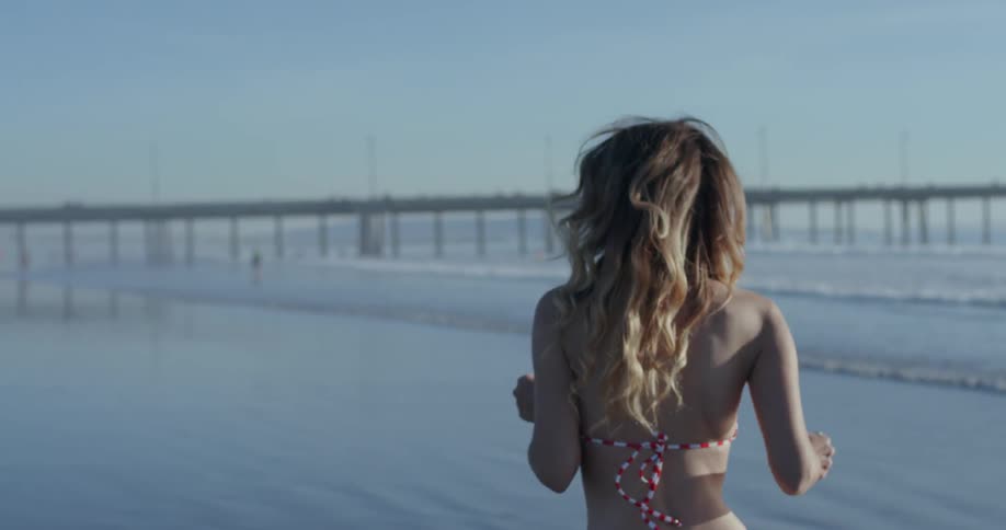 A woman runs a long a beach