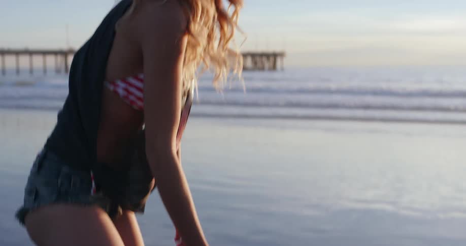 Woman picks up shell on beach and throws it