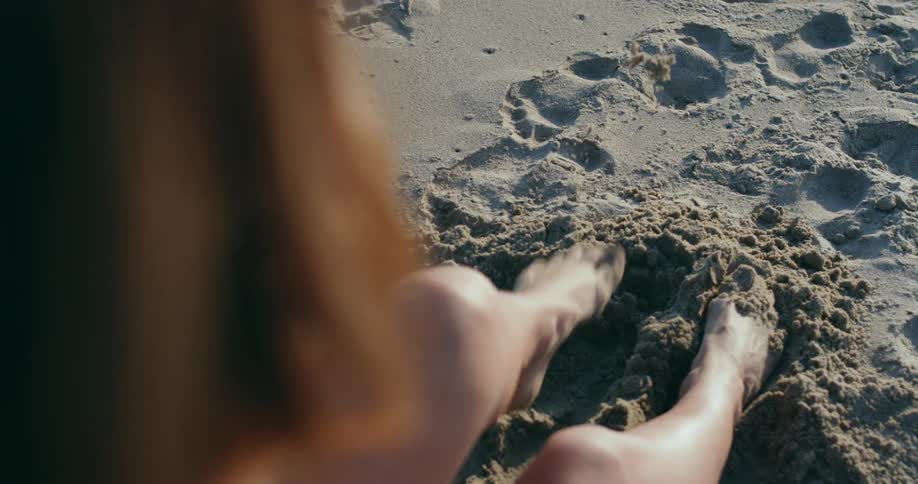 A female kicks sand with her feet