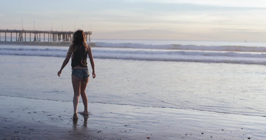 A woman on the beach throwing a stone in the water