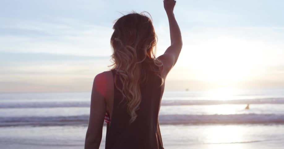 A woman picks up a rocks and throws it to the ocean