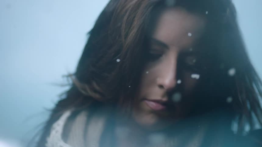 Close up of a woman looking down while snow falls around her