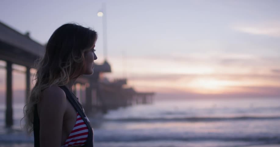 A woman walks on the beach during sunset