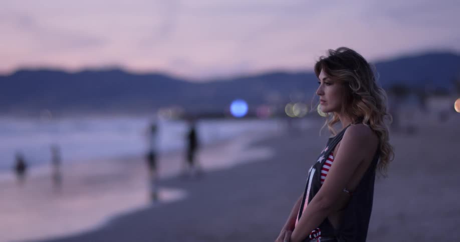 Woman smiles when the child comes to her on the beach at sunset next to the sea