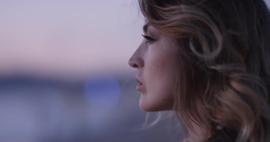 The profile of a woman looking up and around at sunset