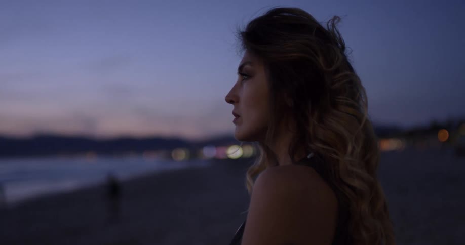 A woman fixes her hair blowing in the wind by the beach