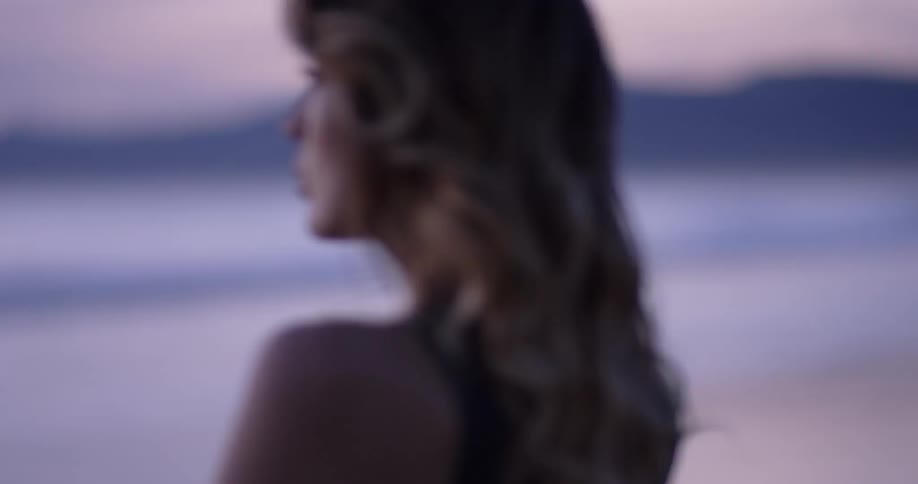 A woman standing on the beach looking at the ocean