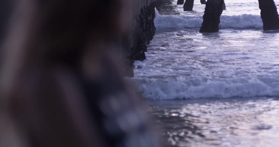 A white woman stands on the beach and looks out at the water