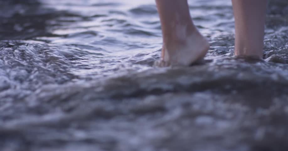 Woman walking barefoot on the shores of a beach