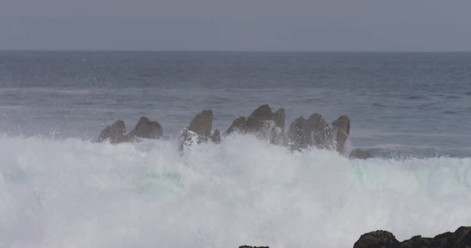 Foamy waves crash over the rocks in the ocean