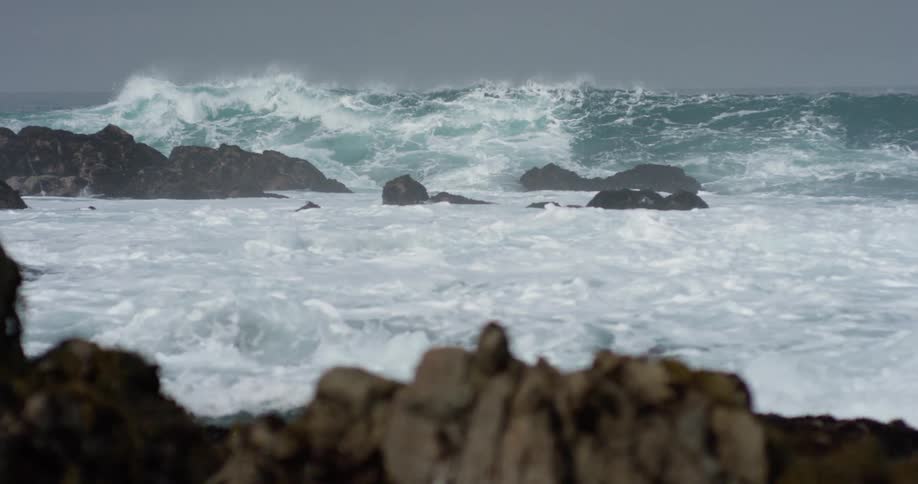 The shore has many rocks with large waves crashing