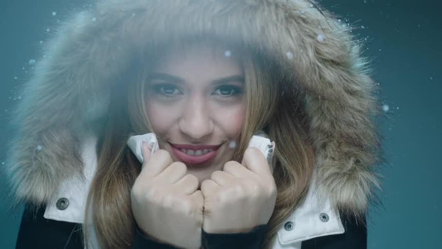 Snow falling around a woman in a fur lined hood