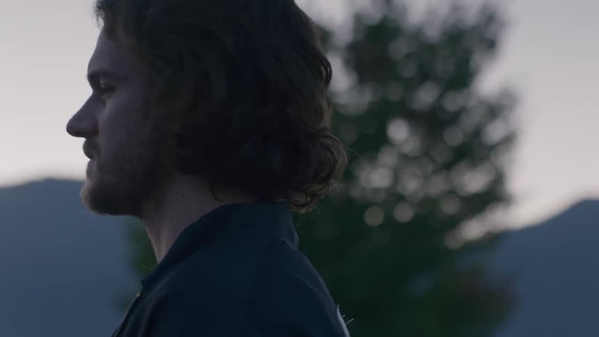 A man standing outside at sunset turns and looks behind him