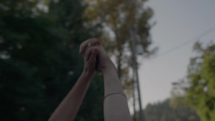 A young couple hold hands and embrace in the back of a moving pickup truck on a sunny day