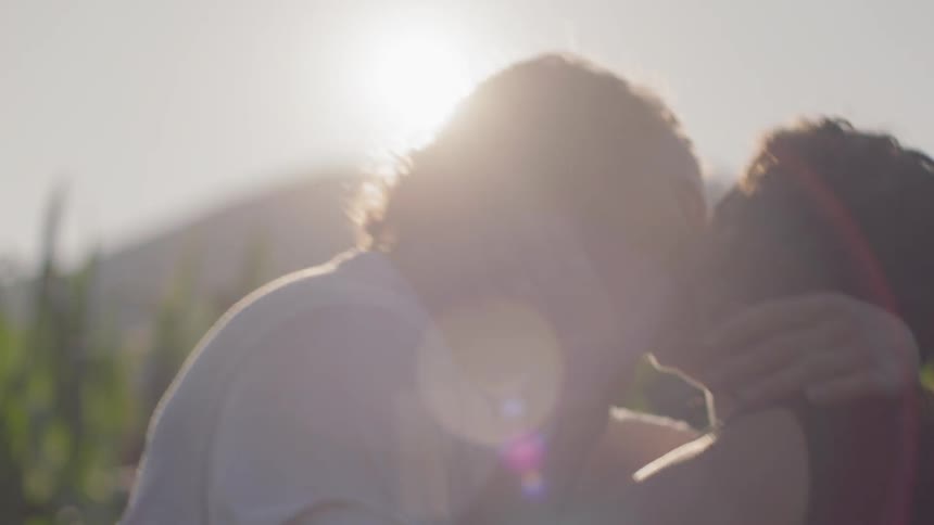 A man and woman embrace and kiss and dip on a sunny day