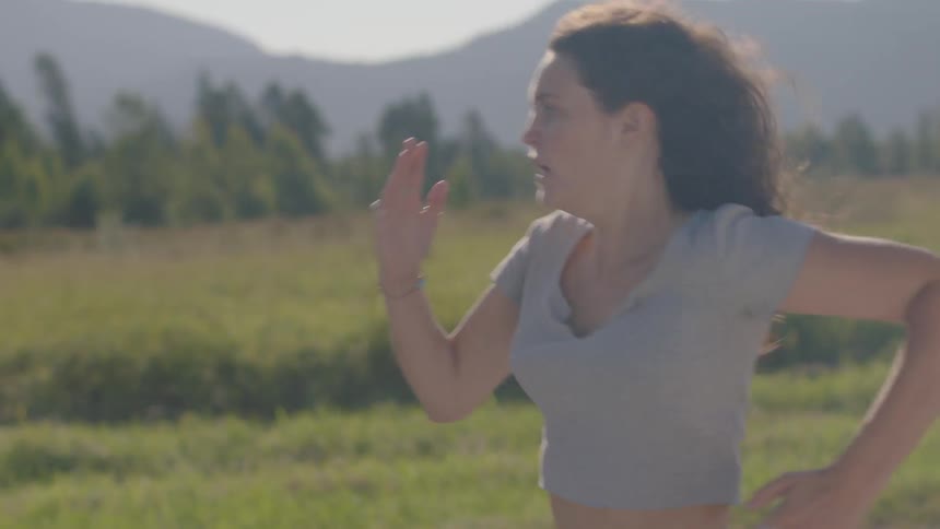 Woman runs in the green field during daylight