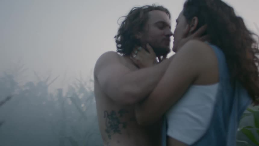 A man and a woman kiss in a cornfield